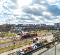 Výhľad na rušnú ulicu v Bratislave - Ružinov, Súmračná, s električkou a parkom.