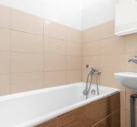 Kúpeľňa s vaňou a umývadlom v 1-izbovom byte, béžová dlažba.