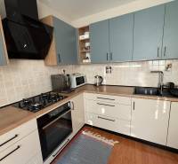 Kuchyně v 3-pokojovém bytě s kachličkovaným obkladem a podlahou s dřevěným dekorem.