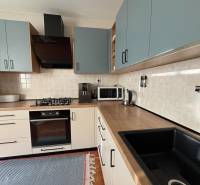 Kuchyňská linka v 3-pokojovém bytě s podlahou s dřevěným dekorem a spotřebiči.