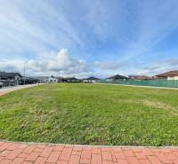 Pohled na prostorný stavební pozemek v Kočovcích, obklopený rodinnými domy.