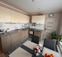 Kuchyně v 3-pokojovém bytě se světlými skříňkami a jídelním stolem.