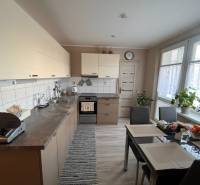 Kuchyně ve 3-pokojovém bytě se stolem, spotřebiči a rostlinami.