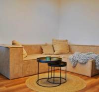 Obývací pokoj v 3pokojovém bytě s pohodlnou sedačkou a podlahou s dřevěným dekorem.