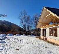 Zimní stavba chaty u ulice v Mýtě pod Ďumbierom v zasněžené krajině.