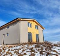 Chata v Dolní Lehotě s dřevěným dekorem, zasněžený pozemek a zamračená obloha.