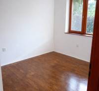 Pokoj s dřevěným dekorem, bílými stěnami, oknem, bez nábytku ve 3-pokojovém bytě.