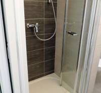 Sprchový kout s dveřmi nacházející se v garsonce na ulici Bodona.