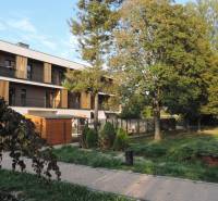 Bytový dům na ulici Bodona, obklopený zelení a stromy, ideální pro bydlení v garsonce.