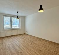 Prostorný pokoj ve 3-pokojovém bytě s podlahou s dřevěným dekorem a visícími lampami.