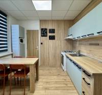 Kuchyně ve 3-pokojovém bytě s jídelním stolem a podlahou s dřevěným dekorem.