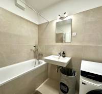 Koupelna v 2-pokojovém bytě s vanou, umyvadlem a pračkou.