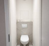 Toaleta se závěsnou mísou a jednoduše laděným obkladem v 2-pokojovém bytě.