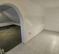 Interiér obchodních prostor s klenutým průchodem a kombinovanými podlahami.