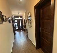 Chodba v rodinném domě s podlahou s dřevěným dekorem a dekorativním zrcadlem na stěně.