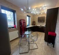 Kuchyně v rodinném domě s podlahou s dřevěným dekorem a skleněným stolem.