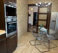 Kuchyně v rodinném domě s podlahou s dřevěným dekorem a skleněným stolem.