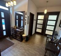 Interiér rodinného domu s podlahou s dřevěným dekorem, úložným prostorem a dekorativním osvětlením.