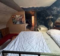 Podkrovní ložnice v rodinném domě s obrazem a modrou stěnou plnou vzorů.