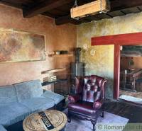 Obývací pokoj v rodinném domě s koženým křeslem a kachlovými kamny.