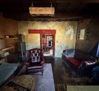 Rustikální obývací pokoj v rodinném domě s koženými křesly a podlahou s dřevěným dekorem.