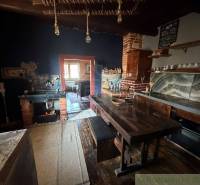 Kuchyně v rodinném domě se starožitným interiérem, dřevěným stolem a cihlovou pecí.