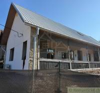 Rodinný dům v Ratkovském Bystrom se zahradou, bílou fasádou a kovovou střechou.