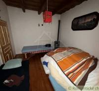 Pokoj v rodinném domě s dřevěným dekorem podlahy a jednoduchým zařízením.