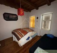 Ložnice v rodinném domě s dekorativními prvky a podlahou s dřevěným dekorem.