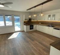 Kuchyně v rodinném domě s dřevěným dekorem podlahy a moderním osvětlením.