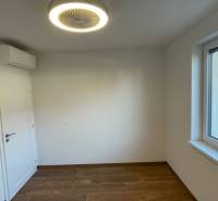 Pokoj v rodinném domě s podlahou s dřevěným dekorem, klimatizací a oknem.