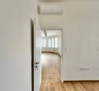 Dveře vedou do kanceláře s podlahou s dřevěným dekorem a klimatizací.