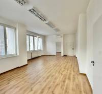 Kanceláře s podlahou s dřevěným dekorem, bílými stěnami a okny nabízejí jasný pracovní prostor.