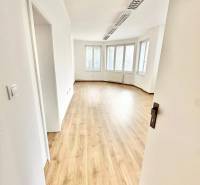 Světlé kanceláře s podlahou s dřevěným dekorem a velkými okny.