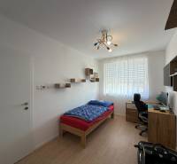 Dětský pokoj ve 3-pokojovém bytě s podlahou s dřevěným dekorem, psacím stolem, postelí.