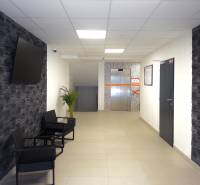 Předsíň v 3-pokojovém bytě s TV na stěně a výtahem v pozadí.