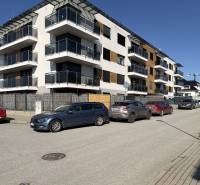 Nové bytové domy na Topoľčianské ulici v Košicích, městská část Západ s auty zaparkovanými vpředu.