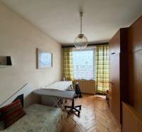 Pokoj v rodinném domě s podlahou s dřevěným dekorem, gaučem a velkou skříní.