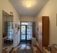 Vstupní hala v rodinném domě s dlažbou, zrcadlem a dekorativním osvětlením.