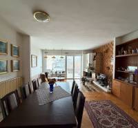 Obývací pokoj v rodinném domě s podlahou s dřevěným dekorem, jídelním stolem a krbem.