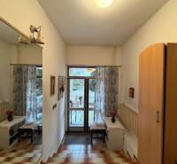 Interiér rodinného domu se zrcadlem, skříní, dlažbou a výhledem na zahradu.