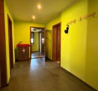 Chodba s věšáky a žlutými stěnami, podlaha s dřevěným dekorem v rodinném domě.