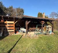 Zahrada rodinného domu v Lutile, s dřevěným přístřeškem a houpačkou na pozemku.