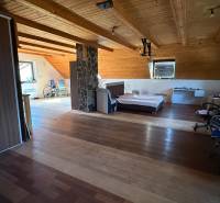 Podkrovní pokoj s postelí, skříní a podlahou s dřevěným dekorem v rodinném domě.