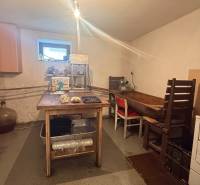 Kuchyně v rodinném domě s jednoduchým nábytkem a zařízením na zpracování potravin.