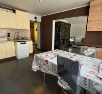 Kuchyně v rodinném domě s keramickým obkladem, jídelním stolem a myčkou.