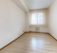 Světlá místnost s oknem a podlahou s dřevěným dekorem v 2-pokojovém bytě.