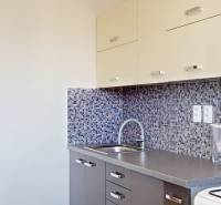 Kuchyně s mozaikovým obkladem v 2-pokojovém bytě, s dřevěným dekorem kuchyňských skříněk.