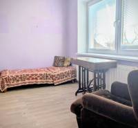 Pokoj v rodinném domě s rozkládací pohovkou a křeslem, podlaha s dřevěným dekorem.