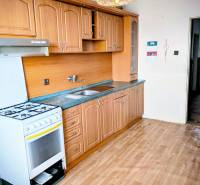 Kuchyně v rodinném domě s klasickou linkou a podlahou s dřevěným dekorem.